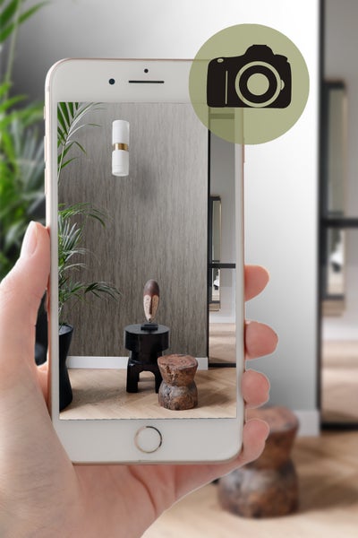 Ansicht eines Wohnraums durch ein Smartphone mit Wandtapete, Leuchte und Dekorationsartikeln