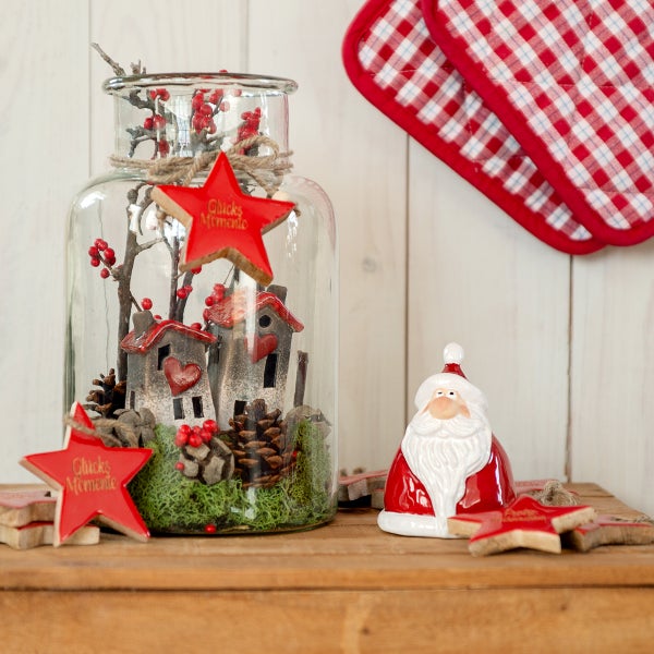 Dekorative Szene mit Glasgefäß, Miniaturhäusern, Tannenzapfen und einer Weihnachtsmannfigur