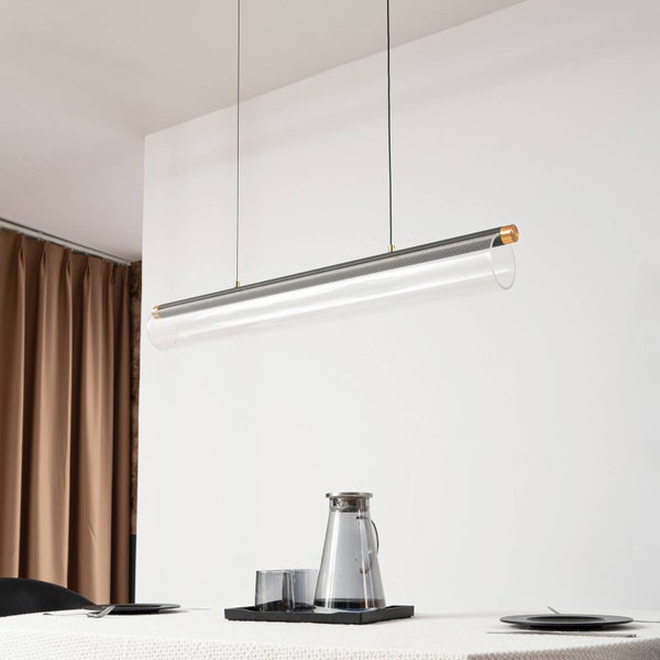 Moderne, minimalistische Pendelleuchte aus Metall und Acryl in Zylinderform über einem Esstisch in einem hellen, organisierten Raum.