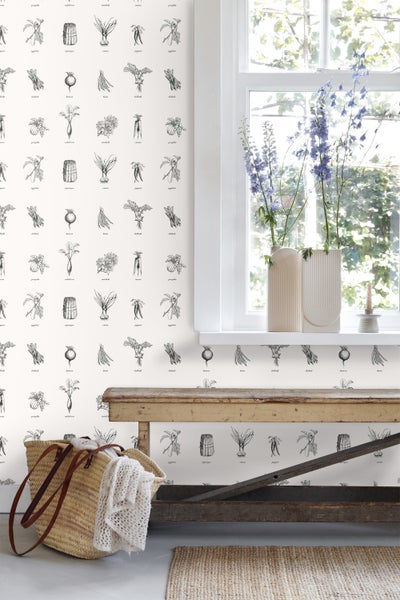 Raumansicht mit Tapete mit Gemüsezeichnungen, Holztisch, Korb und Blumen