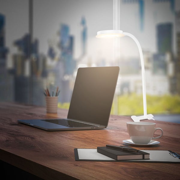 LED Klemmleuchte beleuchtet einen Holzschreibtisch mit Laptop, Notizbuch und Kaffeetasse in einem modernen Büro.