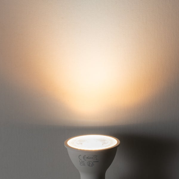 GU10 LED Strahler mit warmweißem Lichtkegel auf einer Wand.