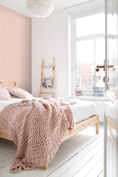 Helles Schlafzimmer mit Holzbett, Decke und Leiterregal