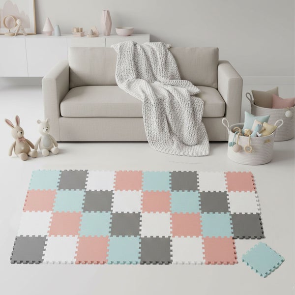 Ein helles Kinderzimmer mit einem weichen Puzzle-Spielteppich aus Schaumstoff im Karomuster vor einem Sofa mit Strickdecke und Stofftieren.