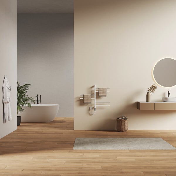 Modernes, helles Badezimmer mit freistehender Badewanne, wandmontiertem Handtuchheizkörper, schwebendem Waschtisch, rundem Spiegel und Holzboden.