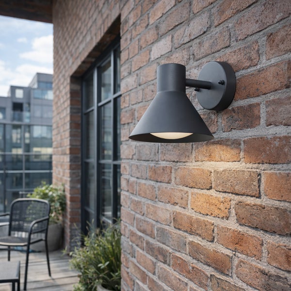 Moderne Außenwandleuchte aus Metall in Kegelform an einer Ziegelwand auf einem Balkon.