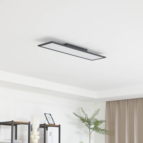 Moderne, rechteckige LED-Deckenleuchte mit schwarzem Metallrahmen an einer weißen Decke in einem hellen, minimalistisch eingerichteten Wohnraum.