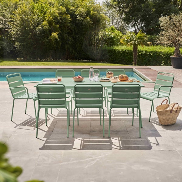 Modernes Gartenmöbel-Set aus grünem Metall mit Tisch und sechs Stühlen auf einer Terrasse neben einem Swimmingpool im Garten.