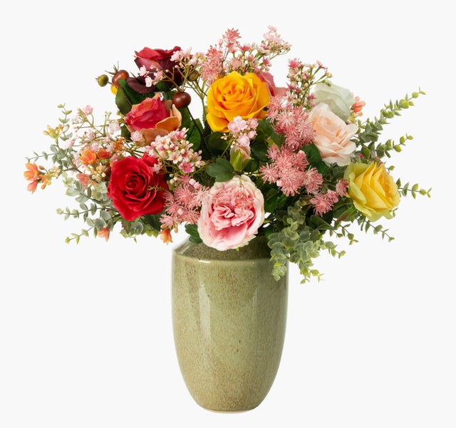 Künstlicher Blumenstrauß mit roten, gelben und rosa Rosen sowie grünem Blattwerk in einer beigen Keramikvase.