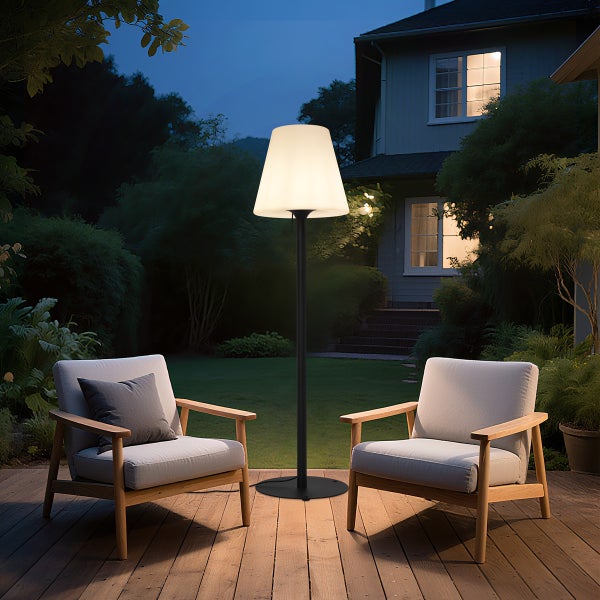 Moderne Stehleuchte für den Außenbereich auf einer Holzterrasse mit zwei Sesseln aus Holz in einem nächtlichen Garten.