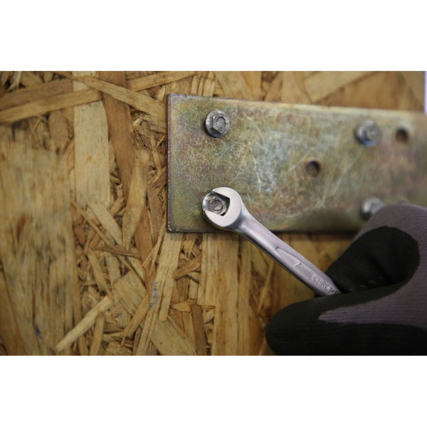 Ein Maulschlüssel zieht eine Schraube auf einer Metallplatte fest, die an einer Holzkonstruktion befestigt ist