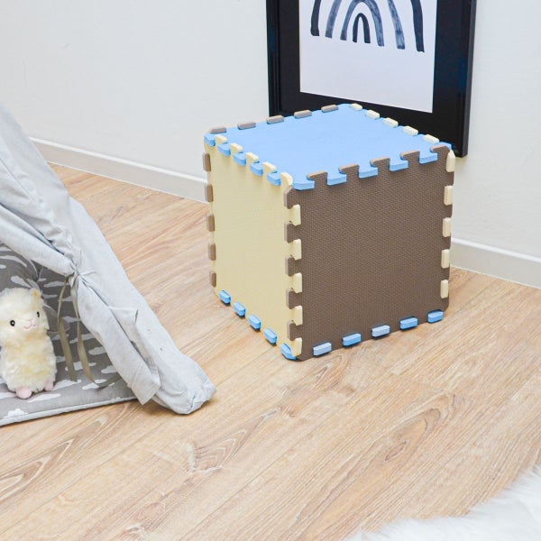 Würfel aus ineinandergreifenden Schaumstoff-Puzzlematten in einem hellen, organisierten Kinderzimmer auf Holzlaminat neben einem Spielzelt.