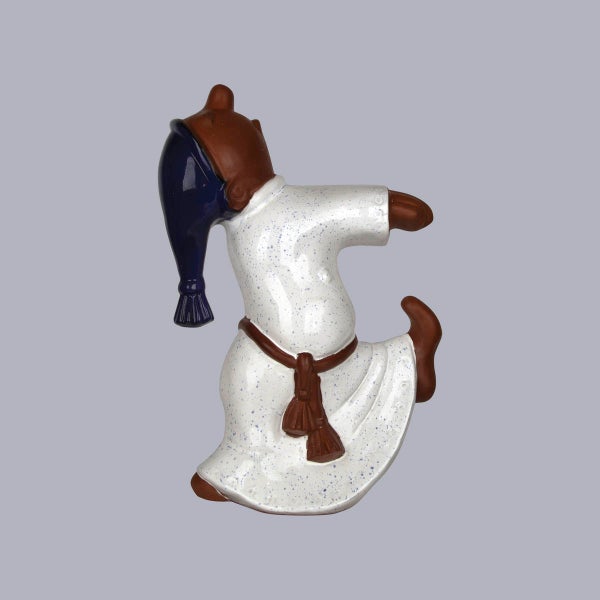 Dekofigur aus Keramik, stilisierte Person in weißem Gewand und blauer Kapuze, dynamische Pose.