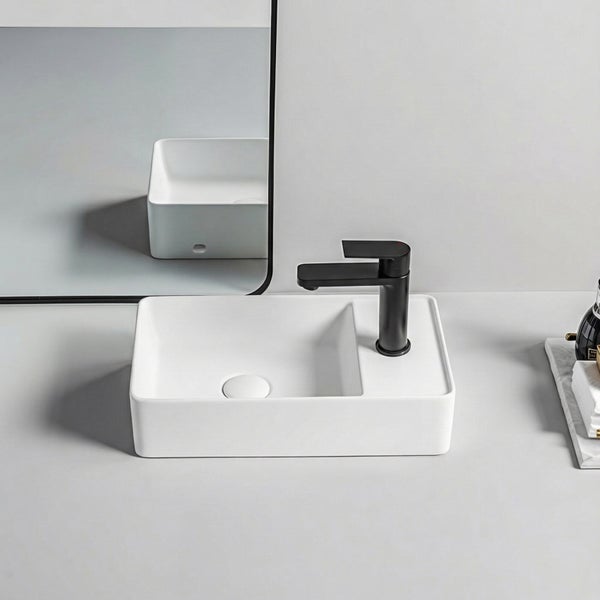 Helles, modernes Badezimmer mit einem weißen rechteckigen Aufsatzwaschbecken, einer schwarzen Armatur und einem gerahmten Spiegel.