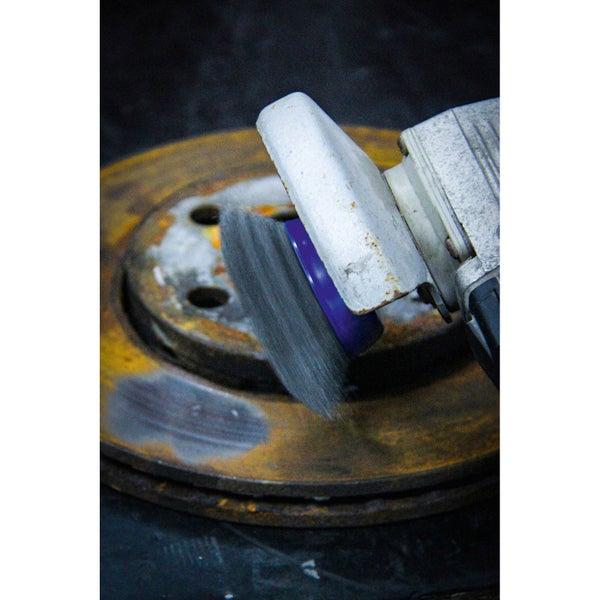 Drahtbürstenaufsatz für Bohrmaschine im Einsatz auf rostiger Metallscheibe