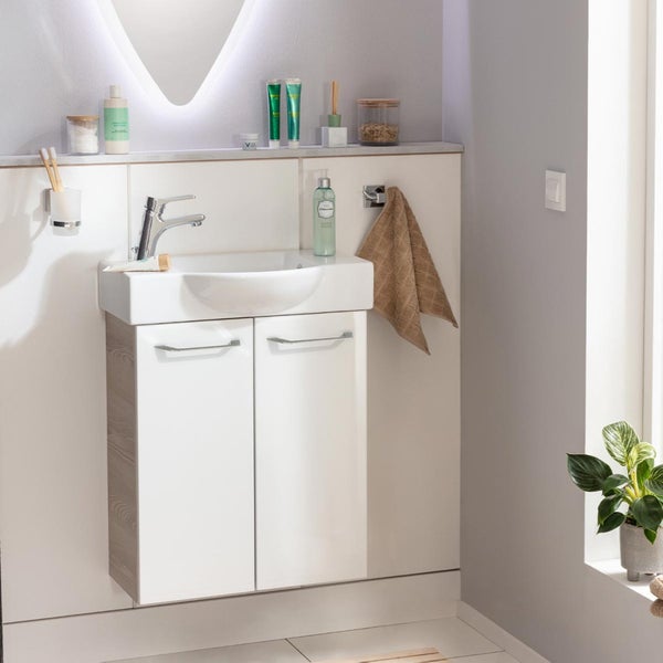Badezimmer mit Waschtisch, Armatur, Handtuch und Dekorationen in hellem und organisiertem Design