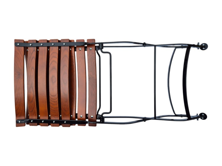 Zusammengeklappter Gartenstuhl aus Holzlatten mit einem Gestell aus schwarzem Metall.