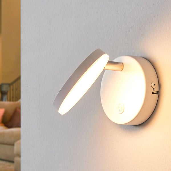 Moderne LED-Wandleuchte in Weiß mit schwenkbarem Kopf in Scheibenform und integriertem Schalter an der runden Halterung.
