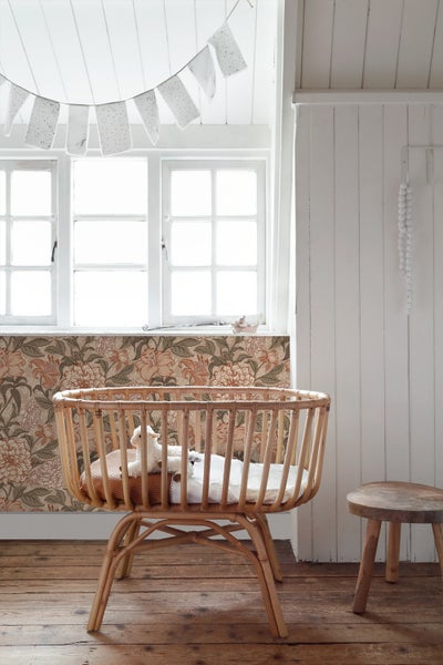 Zimmer mit Gitterbett, Hocker, Fenster und floraler Tapete