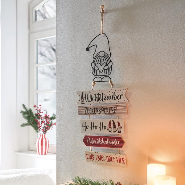 Weihnachtliche Wanddekoration zum Aufhängen aus Holz mit Wichtelmotiv und mehreren Schildern mit festlichen Schriftzügen für die Adventszeit.