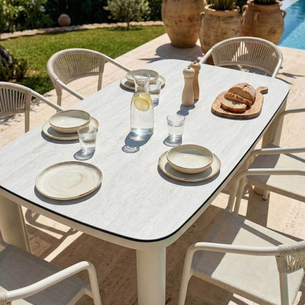 Moderner Gartentisch mit Steinoptik-Platte und Gartenstühlen mit Seilgeflecht auf einer Terrasse mit Pool.