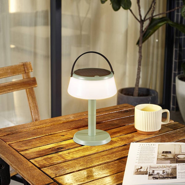 Solar-Tischleuchte auf einem Holztisch im Außenbereich mit integriertem Solarpanel und Tragegriff.