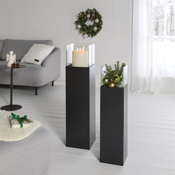 Zwei moderne schwarze Standsäulen mit Glasaufsatz als weihnachtliche Dekoration im Wohnzimmer.