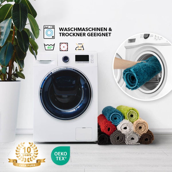 Waschmaschine mit verschiedenen Casa Pura Badteppichen und Hinweisen zur Waschbarkeit und Trocknergeeignetheit.