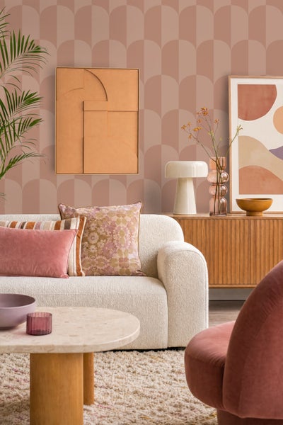 Wohnzimmer mit Vliestapete mit geometrischem Bogenmuster in Erdtönen, helles Boucle Sofa, Sideboard aus Holz und dekorative Wohnaccessoires.