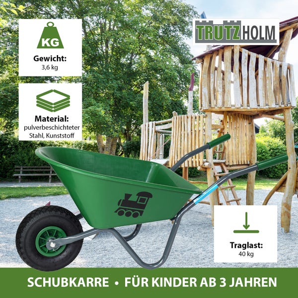 Grüne Kinderschubkarre mit Zugmotiv vor einem Spielplatz