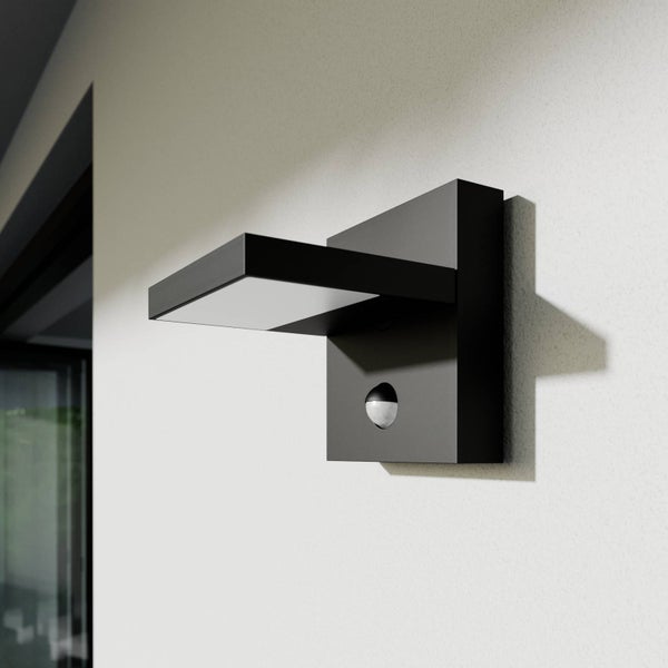 Moderne schwarze LED-Außenwandleuchte mit Bewegungsmelder an einer weißen Wand.