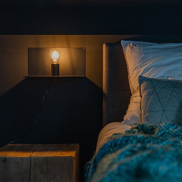 Schlafzimmer mit Bett, Nachttisch und Wandleuchte