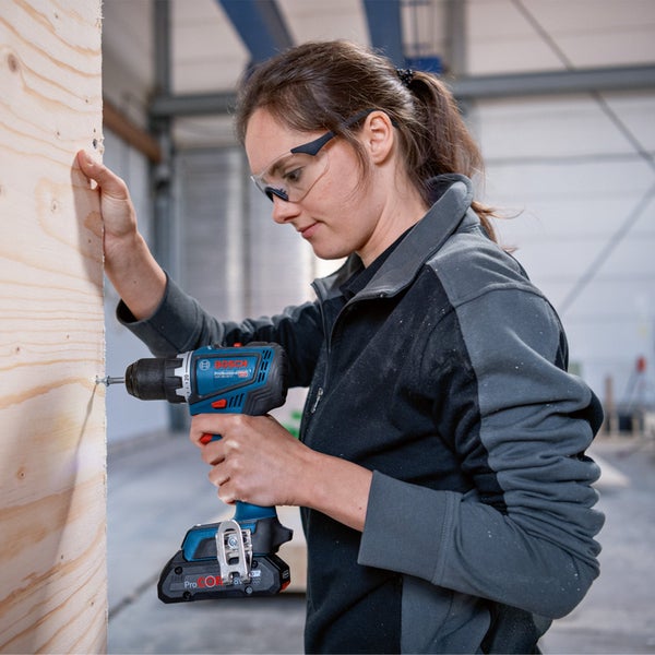Frau schraubt Schraube mit Akku-Bohrschrauber in Holz