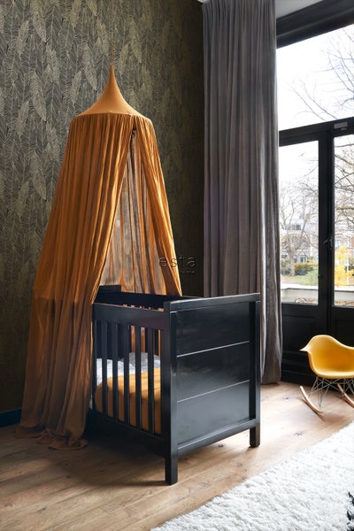 Zimmer mit schwarzem Babybett und Baldachin