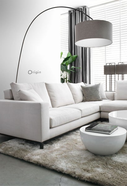 Helles Wohnzimmer mit Ecksofa, Bogenlampe und runden Tischen auf einem Teppich