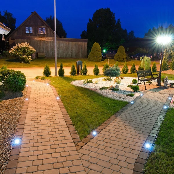 Beleuchteter Gartenweg mit Pflastersteinen und Gartenbank bei Nacht