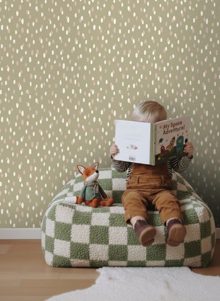 Zimmer mit Kind, das ein Buch auf einem karierten Sitzkissen vor einer Wand mit Tupfenmuster liest