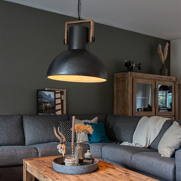 Moderne Pendelleuchte aus Metall und Holz über einem gemütlichen Wohnbereich mit Sofa und Couchtisch in einer Einrichtung im Landhausstil.