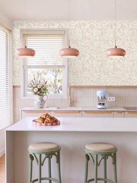 Moderne Küche mit hell gemusterter Blumentapete über einem Fliesenspiegel, Kücheninsel, Barhockern und drei Pendelleuchten.