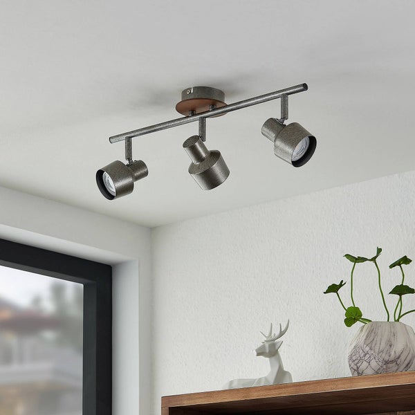 Dreiflammiger Deckenstrahler im Industrie-Design mit Metallschirmen und Holzsockel, an einer Zimmerdecke montiert.