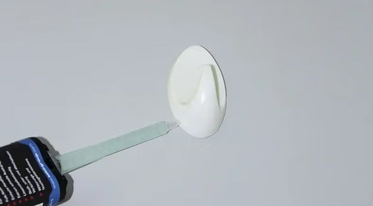 Wandhaken wird mit einer Kartuschenpistole an einer Wand befestigt.