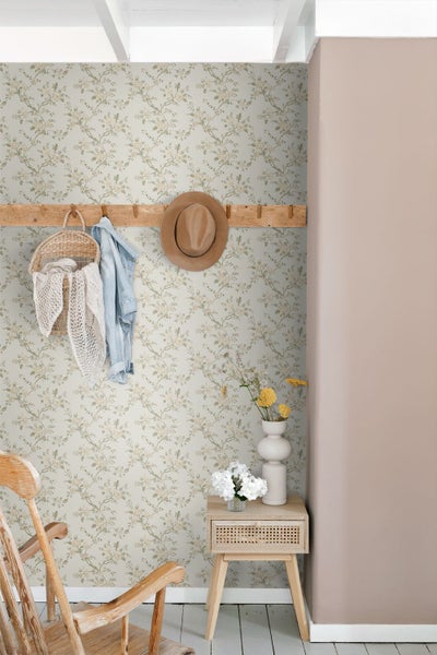 Helles Esszimmer mit floral gemusterter Vliestapete, einem Kaminofen und einem runden Holztisch mit Stühlen vor einem großen Fenster.