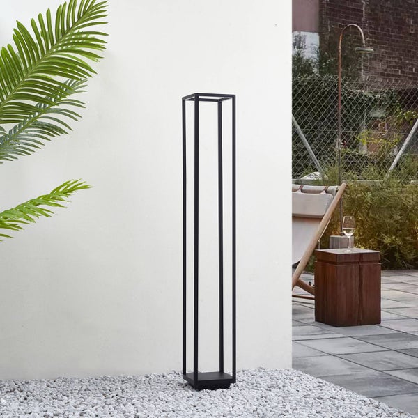 Minimalistische schwarze Außen-Sockelleuchte mit rechteckigem Metallrahmen auf Kies neben einer Wand in einem modernen Außenbereich.