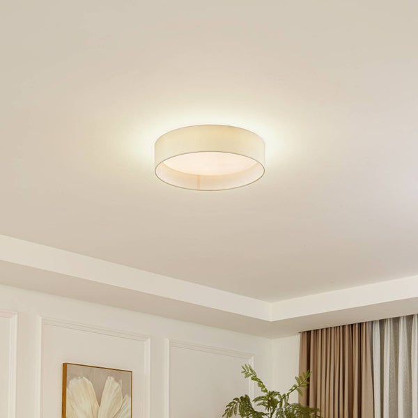 Runde Deckenleuchte mit beigefarbenem Stoffschirm, montiert an einer weißen Zimmerdecke in einem hellen, modern eingerichteten Raum.
