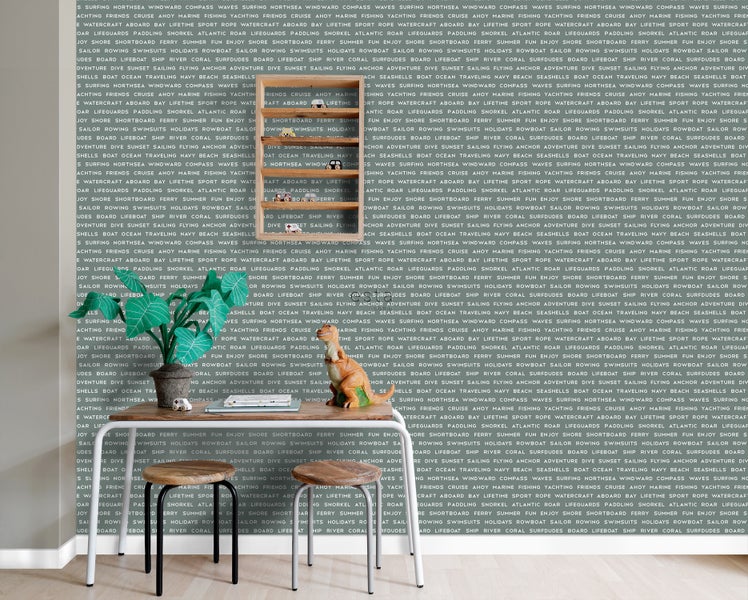 Dekoratives Interieur mit Holzhockern, Tisch, Zimmerpflanze, Dinosaurierfigur und Holzregal mit Spielzeugautos vor einer Wandtapete mit maritimen Motiven