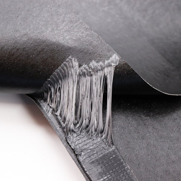 Detailaufnahme einer abgerissenen, schwarzen Dichtungsbahn mit Klebeschicht