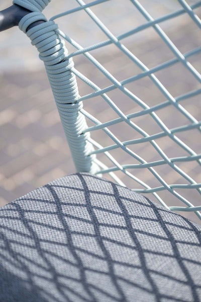 Detail eines Gartenstuhls mit Seilgeflecht an der Rückenlehne und gepolstertem Sitzkissen.