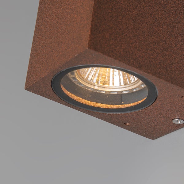 Nahaufnahme einer rechteckigen Wandleuchte mit rostfarbener Oberfläche und runder Lichtquelle.