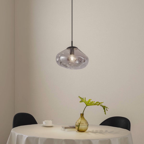 Moderne Hängeleuchte mit organisch geformtem Glasschirm in Rauchgrau über einem gedeckten runden Esstisch.