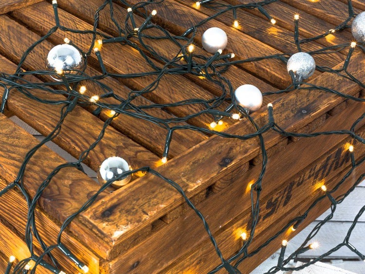 LED Lichterkette mit warmweißen Dioden und silbernen Weihnachtskugeln auf einer rustikalen Holzkiste zur Weihnachtsdekoration